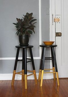 two black and gold stools next to each other in front of a white door