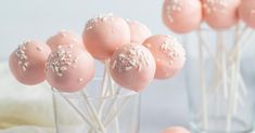 pink cake pops with white sprinkles in a glass vase on a table