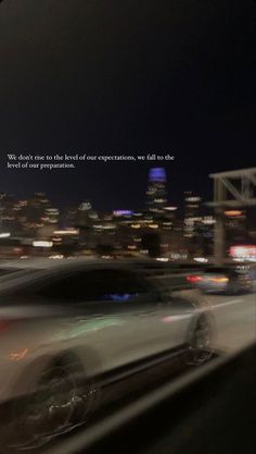 a blurry photo of cars driving down the road at night with a city skyline in the background