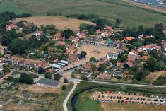 an aerial view of a town with lots of houses and cars parked in the lot