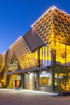 a large building with an unusual design on it's side and lights lit up at night