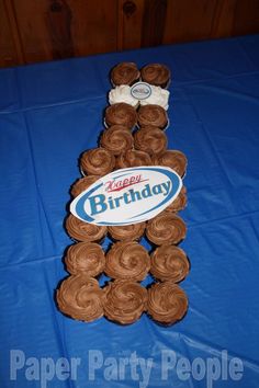 cupcakes are arranged in the shape of a man's legs on a blue tablecloth