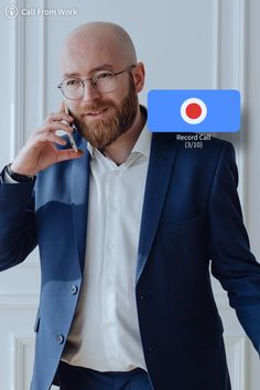 a bald man in a blue suit holding a cell phone to his ear and looking at the camera