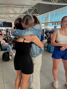 two women hugging each other in an airport