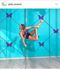 a woman pole dancing in front of a blue wall