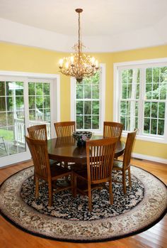 a dinning room with yellow walls and hardwood floors, round rug on the floor