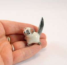 a tiny toy mouse sitting on top of someone's hand with it's tail sticking out