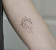 a small heart shaped tattoo with flowers on the left side of the arm and chest