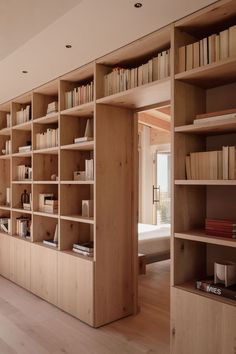 an open bookcase with many books on it in a living room next to a window