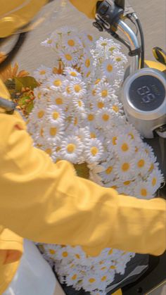 a person on a scooter with daisies in the basket and other flowers