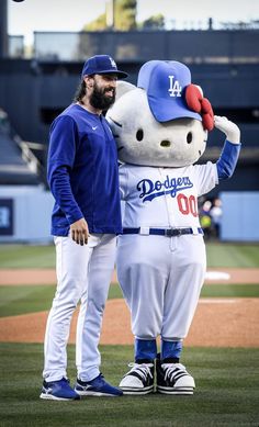 two baseball players standing next to each other on a field with a hello kitty mascot