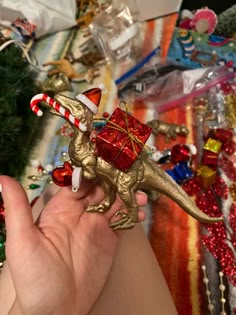 a person is holding a toy dinosaur with a christmas present on it's back