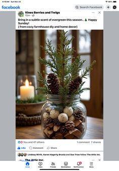 a glass jar filled with pine cones on top of a table next to a candle