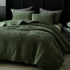 a bed with green bedspread and pillows