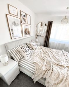 a white bed sitting in a bedroom next to a window with pictures on the wall