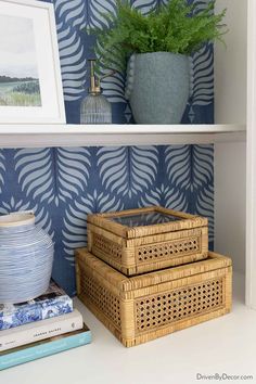 three wicker baskets sit on a shelf next to a blue and white wallpaper