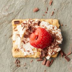 a piece of food with chocolate, cream and a strawberry on it sitting on the ground