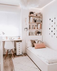 a white room with a bed, desk and shelves filled with books on the wall