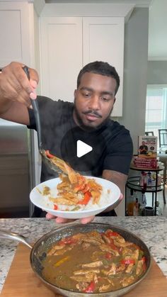 a man holding a plate of food in front of a pan on a kitchen counter