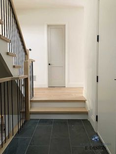 a white door and some stairs in a room with black tile flooring on the ground