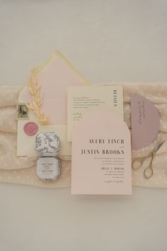 the wedding stationery is laid out on top of an envelope and some other items