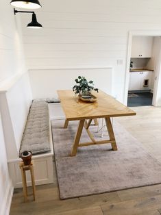 a wooden table sitting on top of a hard wood floor next to a white wall