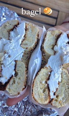 several pieces of bread with white frosting on them sitting in tin foil, next to the words bagel