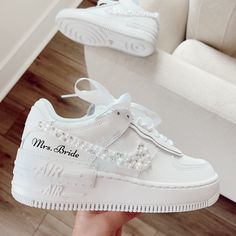 a pair of white shoes with pearls on the soles are being held up by someone's hand