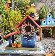 a blue birdhouse sitting on top of a wooden table next to potted plants