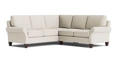 a white sectional couch sitting on top of a wooden leg floor next to a wall