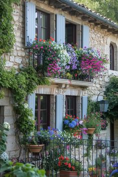 an old stone house with flowers growing on the balconies