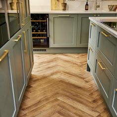 a kitchen with green cabinets and wood flooring in the center, along with a wine rack on the far wall