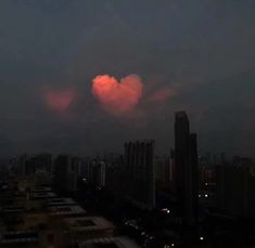 a cloud is seen in the sky over a city at night with buildings lit up