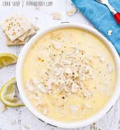 a white bowl filled with soup next to crackers and lemon wedges on a table