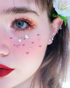 a close up of a person with pink makeup and flowers in her hair, wearing red lipstick