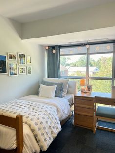 a bedroom with two twin beds and pictures on the wall above them, in front of a window