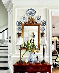 a table with flowers and plates on it in front of a mirror above the stairs