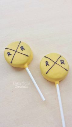 two yellow lollipops sitting on top of each other with crosses painted on them