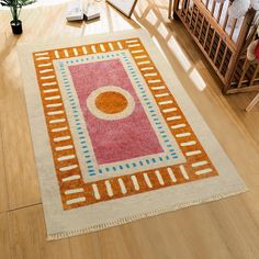 an area rug is on the floor near a baby crib and rocking chair with a potted plant in it