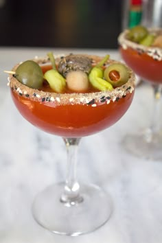 two glasses filled with different types of food on top of a white countertop next to each other