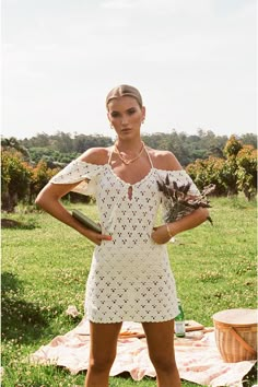 a woman standing in the grass with her hands on her hips and wearing an open shoulder dress