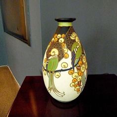 a vase with birds painted on it sitting on a table next to a framed painting