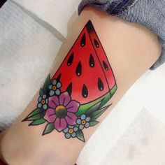 a watermelon tattoo with flowers and drops on the side of its leg is shown