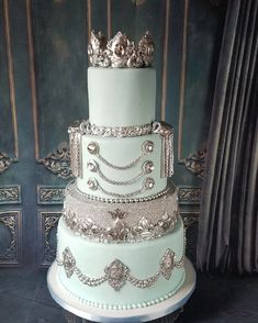 a three tiered cake with silver decorations on it's sides and a crown on top