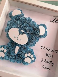 a blue teddy bear made out of rolled paper in a shadow box with the date on it