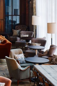 a living room filled with lots of furniture next to a tall window covered in curtains