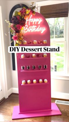 a pink stand with cupcakes and candles on it