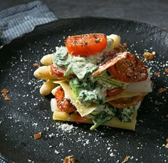 a black plate topped with pasta and vegetables