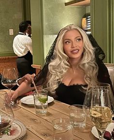 a woman sitting at a table with wine glasses in front of her