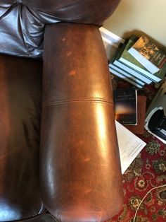 a brown leather recliner sitting on top of a carpeted floor next to a pile of books